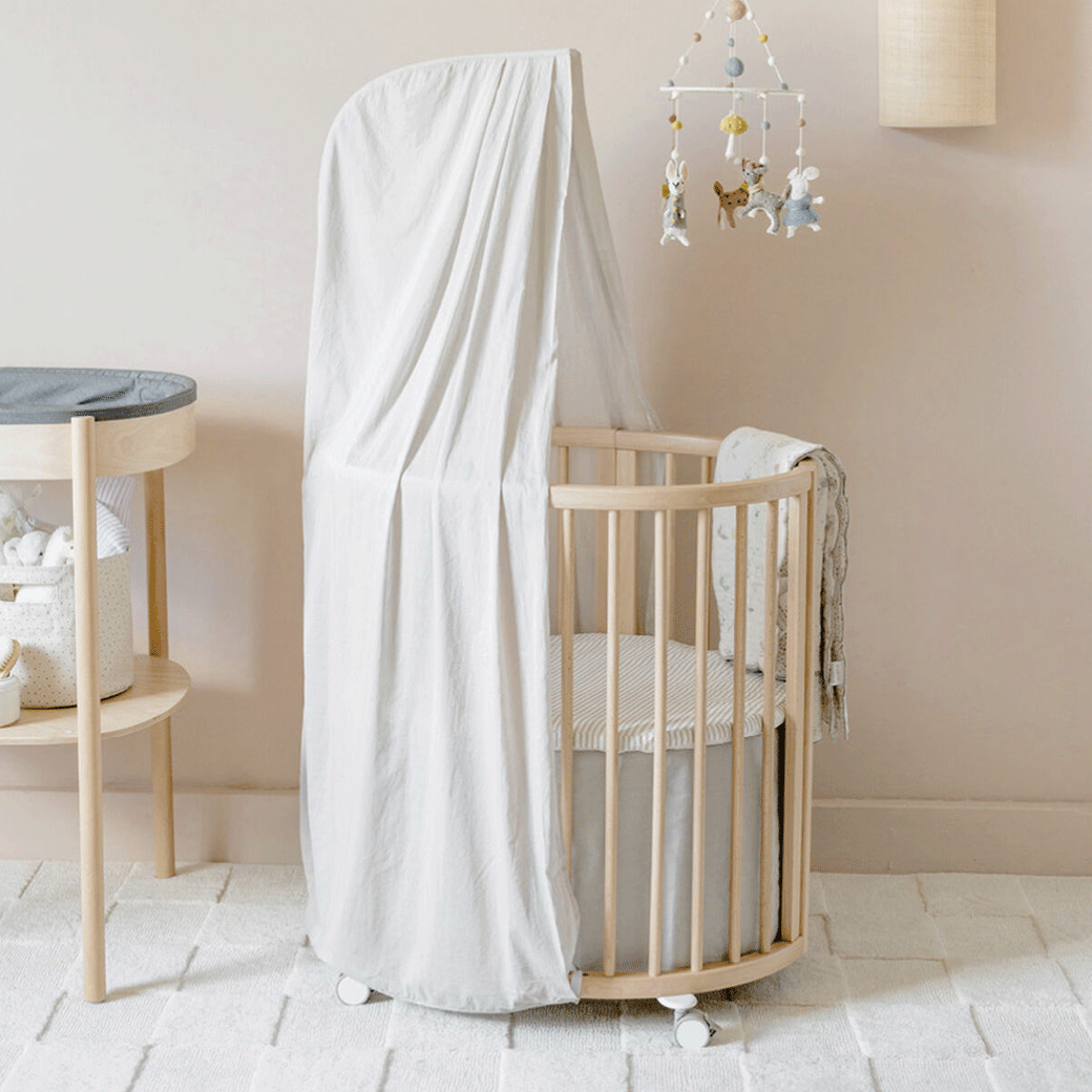 An empty crib equipped with the Stokke Sleepi V3 Canopy by Pehr in -- Color_Grey