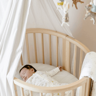 A baby sleeping in a crib equipped with the Stokke Sleepi V3 Canopy by Pehr in -- Color_Grey