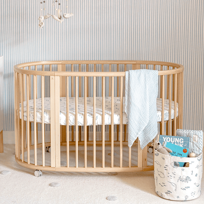 An empty crib equipped with a Stokke's Sleepi V3 Fitted Sheet By Pehr in -- Color_Life Aquatic