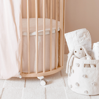 A close up of an empty crib equipped with The Stokke Sleepi V3 Mini Bed Skirt by Pehr