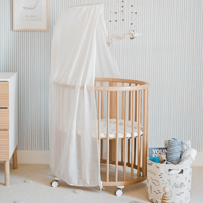An empty crib equipped with a Stokke's  Sleepi V3 Mini Fitted Sheet By Pehr in -- Color_In The Wild