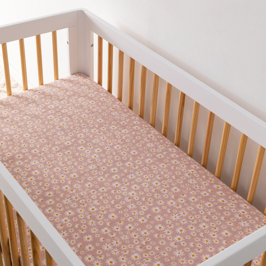 An empty crib equipped with the Babyletto's Crib Sheet in GOTS Certified Organic Muslin Cotton in -- Color_Daisy