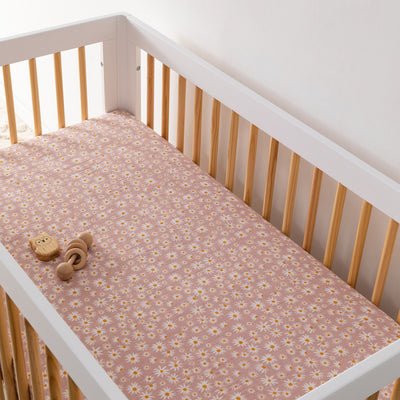 A crib  with toy equipped with the Babyletto's Crib Sheet in GOTS Certified Organic Muslin Cotton in -- Color_Daisy