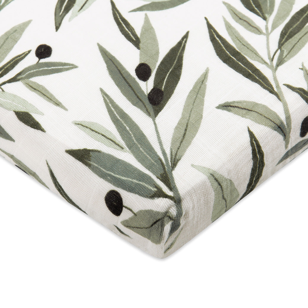 Corner view of Babyletto's All-Stages Midi Crib Sheet In GOTS Certified Organic Muslin Cotton in -- Color_Olive Branches