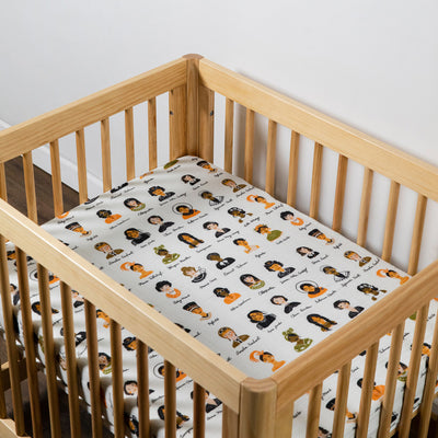 Empty crib equipped with Babyletto's All-Stages Midi Crib Sheet In GOTS Certified Organic Muslin Cotton in -- Color_Women In History