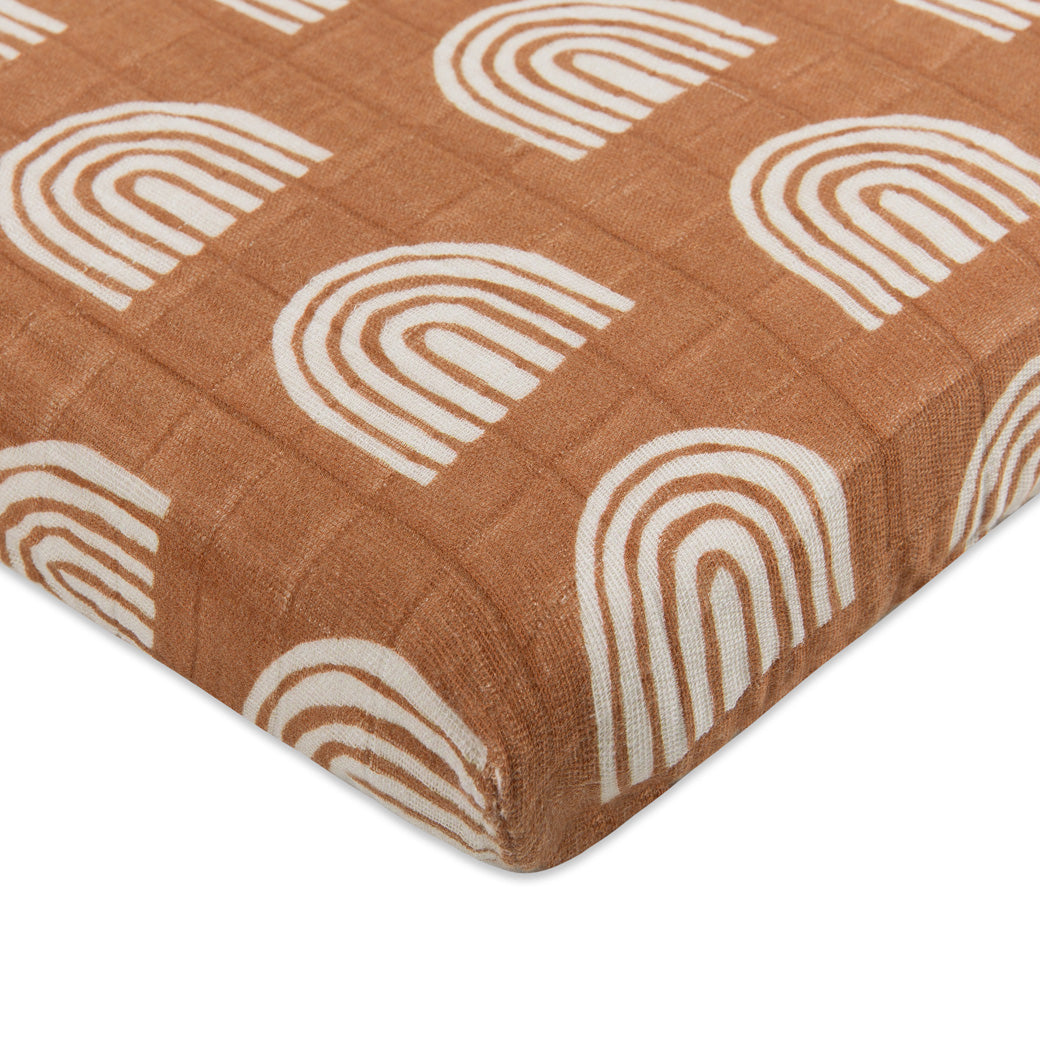 Corner view of Babyletto's All-Stages Midi Crib Sheet In GOTS Certified Organic Muslin Cotton in -- Color_Terracotta Rainbow