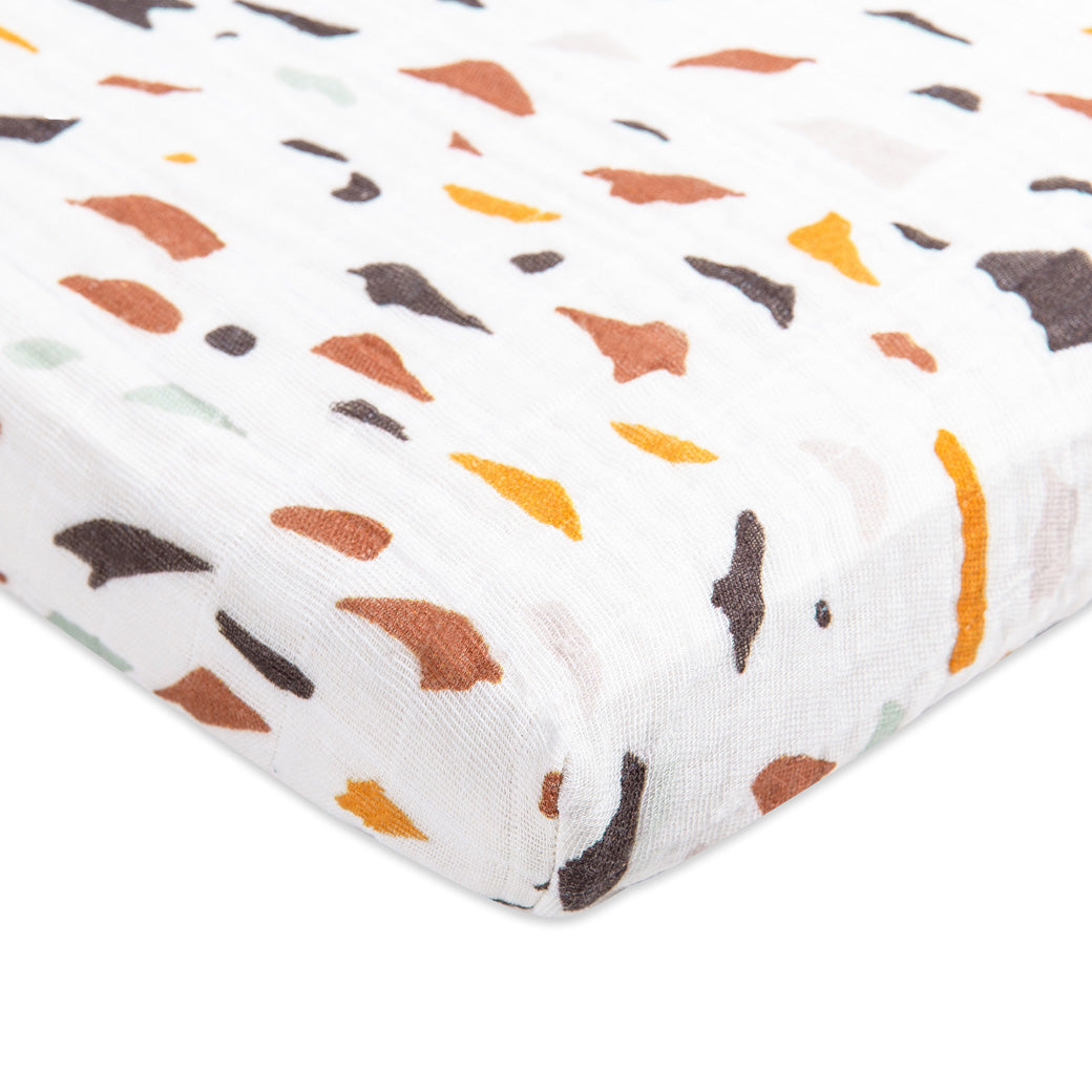 Corner view of Babyletto's All-Stages Midi Crib Sheet In GOTS Certified Organic Muslin Cotton in -- Color_Terrazzo