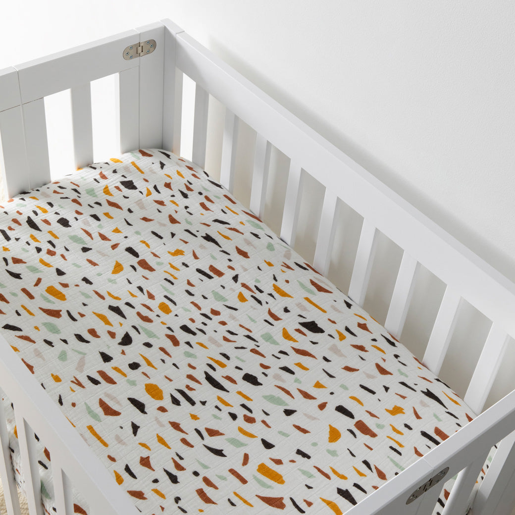 Empty crib equipped with Babyletto's Mini Crib Sheet in -- Color_Terrazzo
