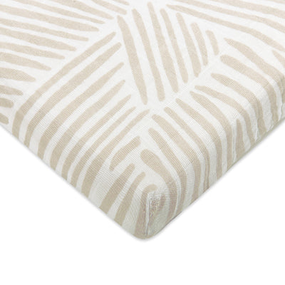 Corner view of Babyletto's All-Stages Midi Crib Sheet In GOTS Certified Organic Muslin Cotton in -- Color_Oat Stripe