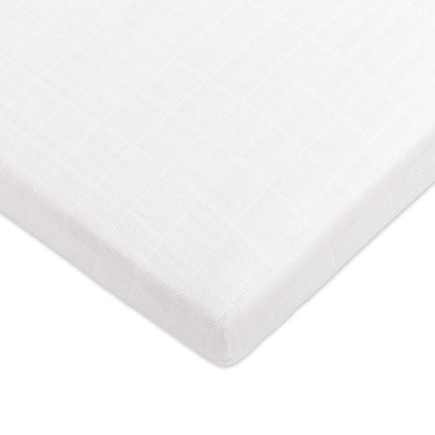 Corner view of Babyletto's All-Stages Midi Crib Sheet In GOTS Certified Organic Muslin Cotton in -- Color_White