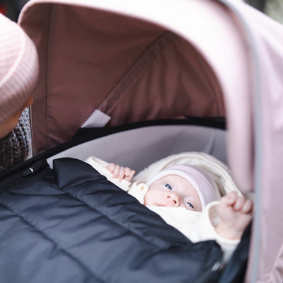 A close up of a newborn in the Thule Shine Bassinet on the Thule Shine Stroller in Misty Rose