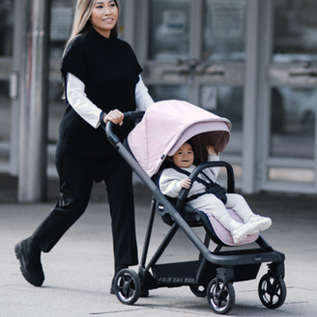 Mother walking her kid in the Thule Shine Stroller in -- Color_Misty Rose