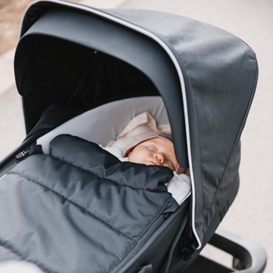A close up of a newborn in the Thule Shine Bassinet on the Thule Shine Stroller in Black