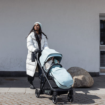 Mother pushing her baby in the Thule Shine Stroller in -- Color_Alaska