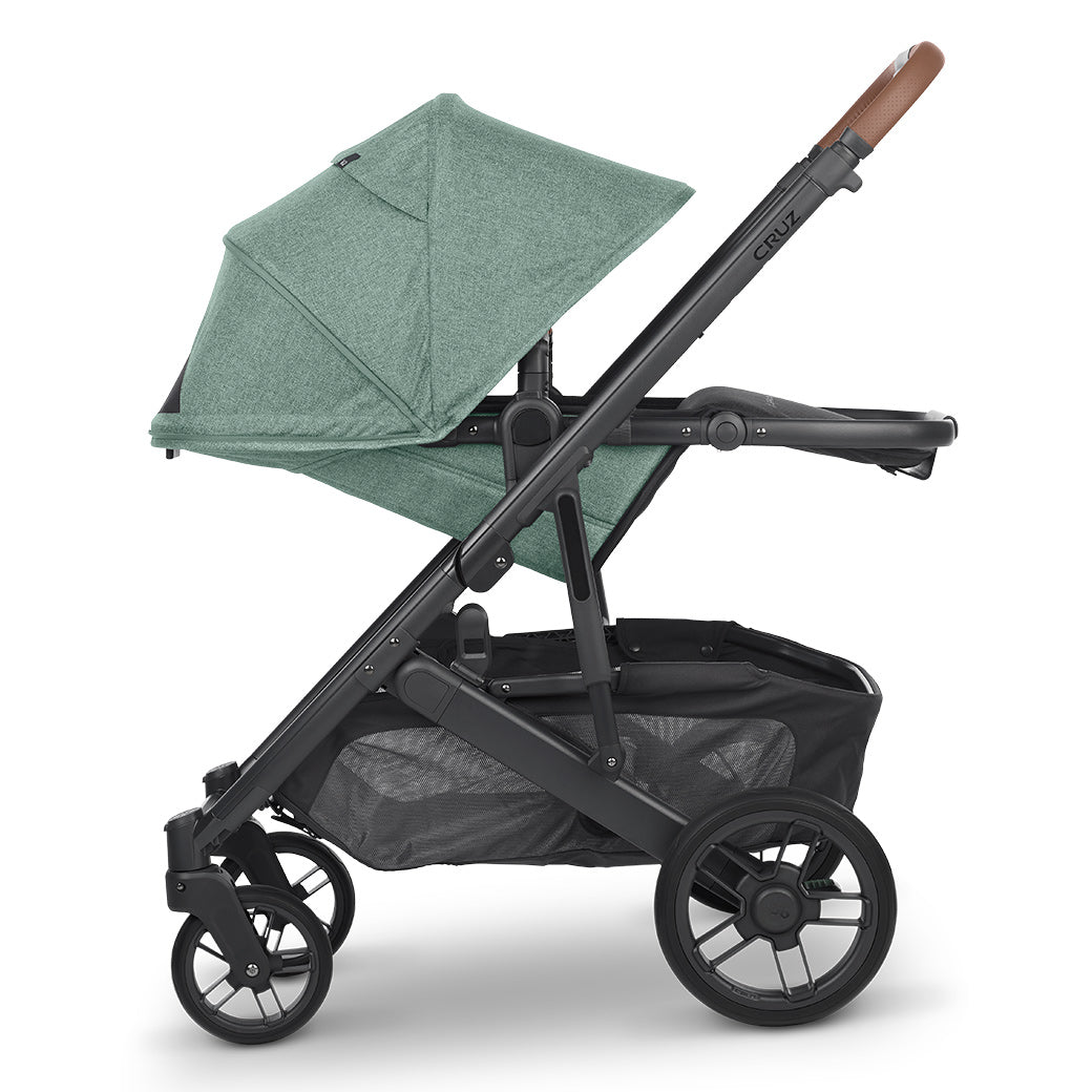 Side view of UPPAbaby CRUZ V2 Stroller with baskets facing right and the shade down in a green color -- Color_Gwen