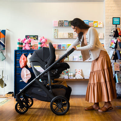 Side view of mom in store with baby in UPPAbaby VISTA V2 Travel System in -- Color_Jake