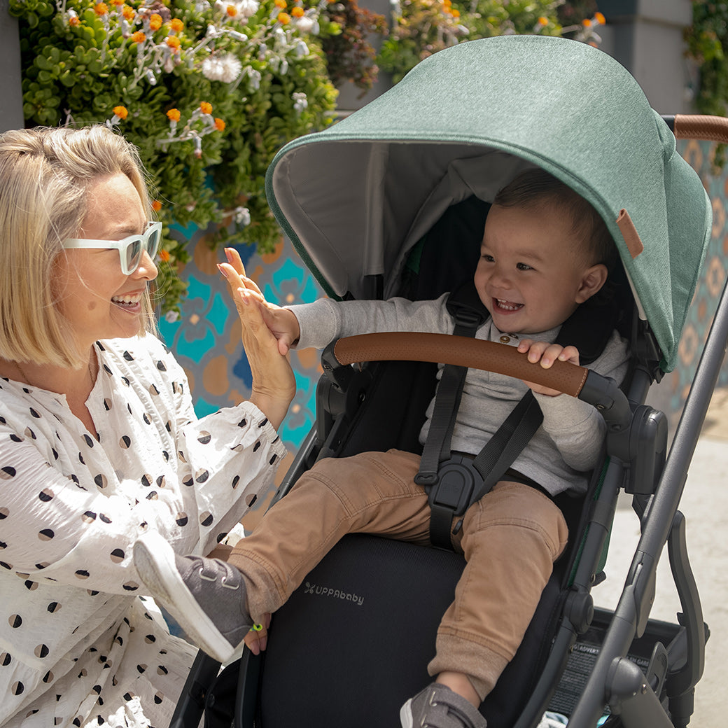 Baby sitting in the UPPAbaby VISTA V2 Travel System stroller and giving mom a high-five in -- Color_Gwen