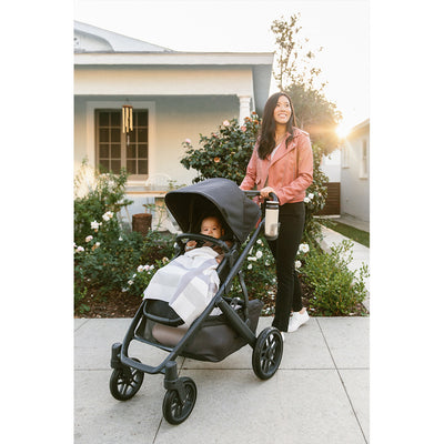 Mom and baby in front of a house and garden with the UPPAbaby VISTA V2 Stroller in -- Color_Jake