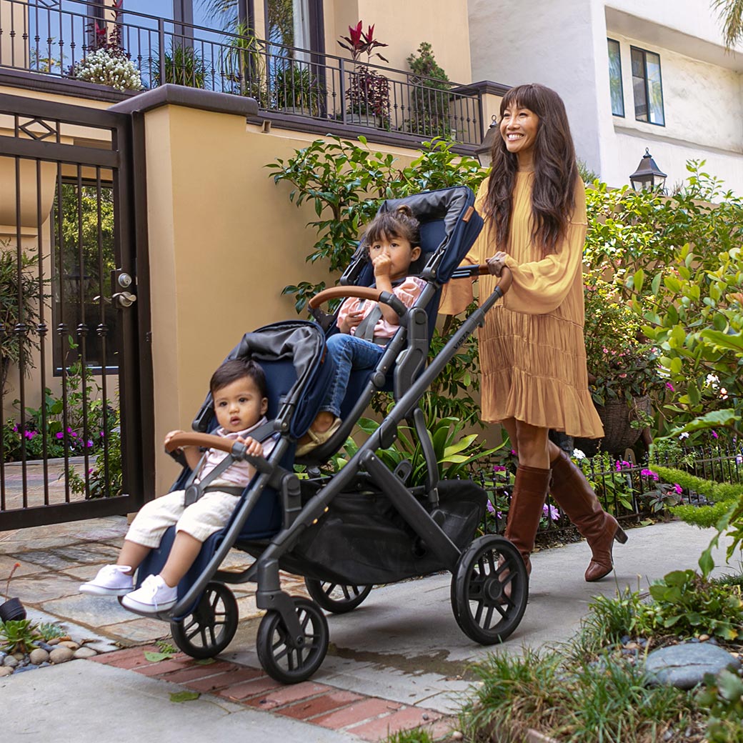 Mom walking her two kids in the UPPAbaby Vista V2 Twin Stroller in Noa -- Lifestyle