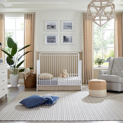 Namesake's Winston 4 in 1 Convertible Crib in a baby room next to a recliner and dresser  in -- Color_Washed White