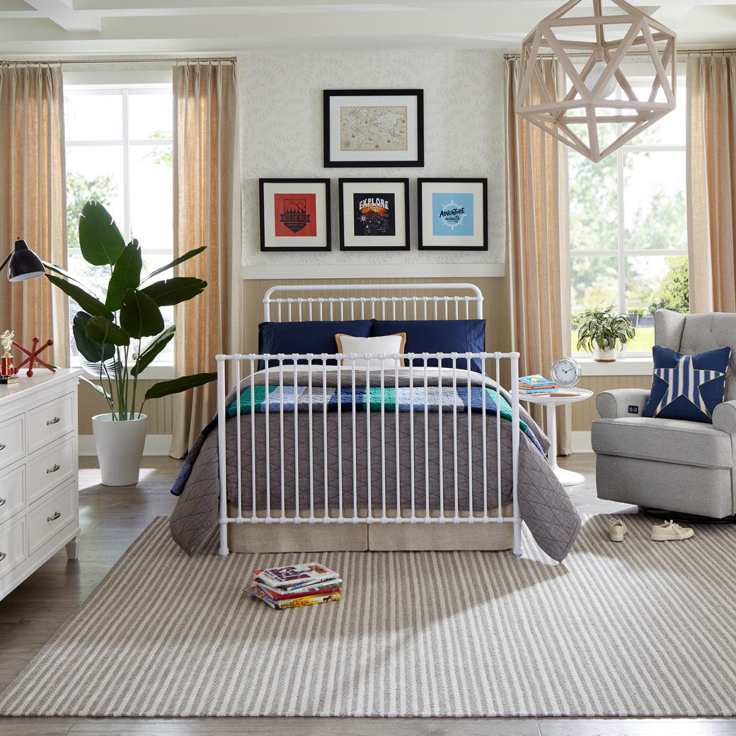 Namesake's Winston 4 in 1 Convertible Crib as full-size bed next to a recliner and dresser  in -- Color_Washed White