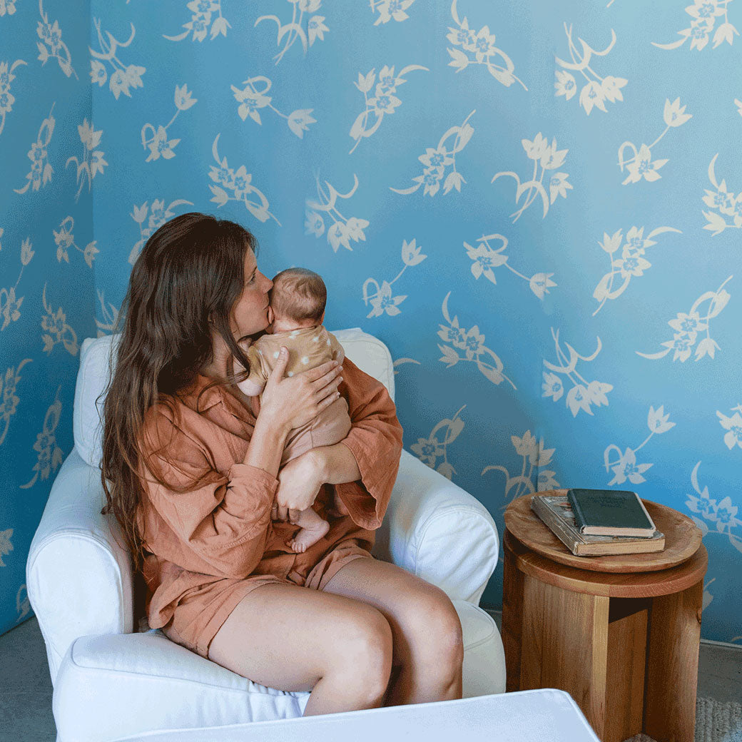 A mother holdig a baby sitting in a chair in a room furnished with Anewall After The Rain Floral Mural