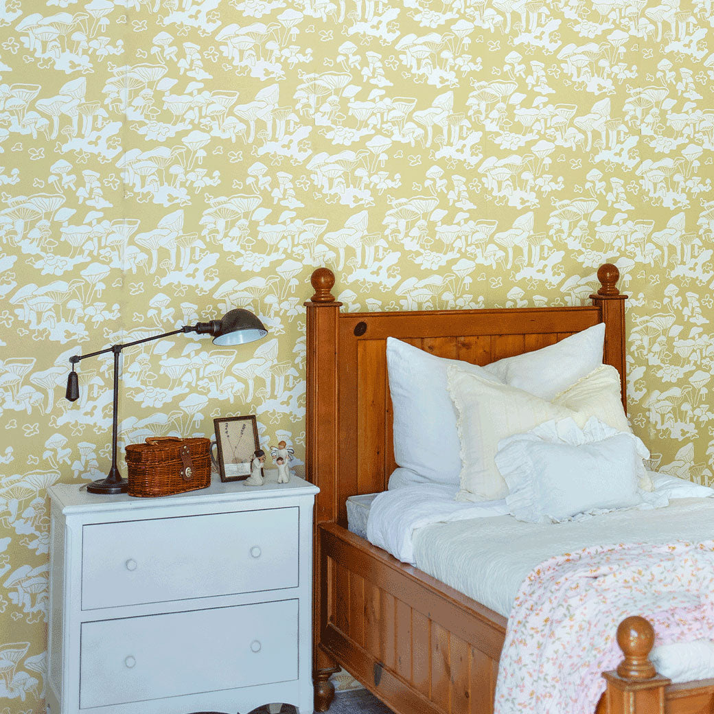 Lifestyle side view of bed and nightstand in a room furnished with Anewall Forest Floor Mushroom Wallpaper
