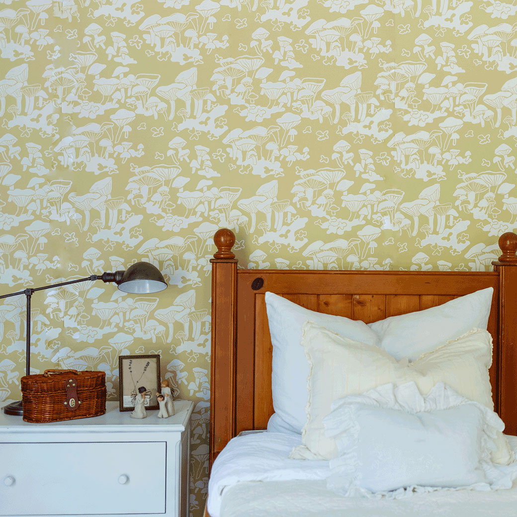 Nightstand with lamp and bed next to the Anewall Forest Floor Mushroom Wallpaper