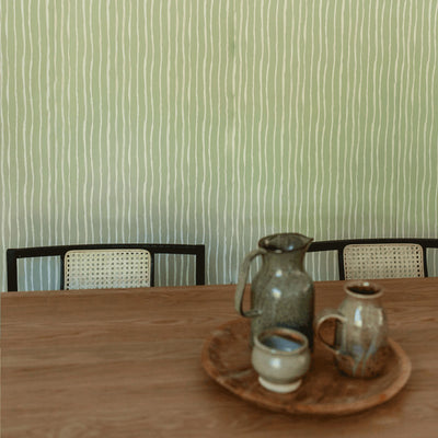 Closeup view of table with chairs and pottery in front of Anewall Soft Stripes Wallpaper