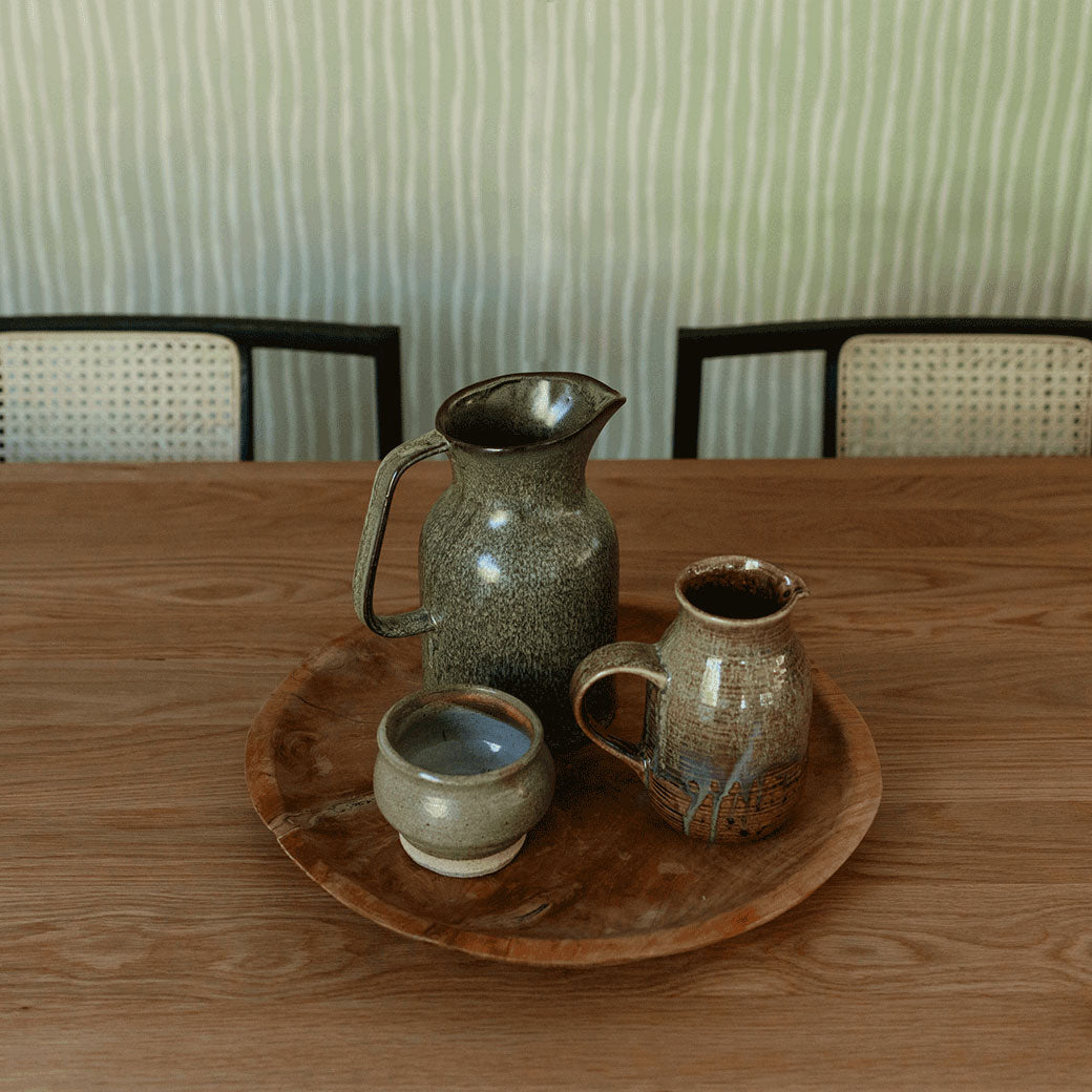 Zoomed in view of pottery on table in front of the Anewall Soft Stripes Wallpaper