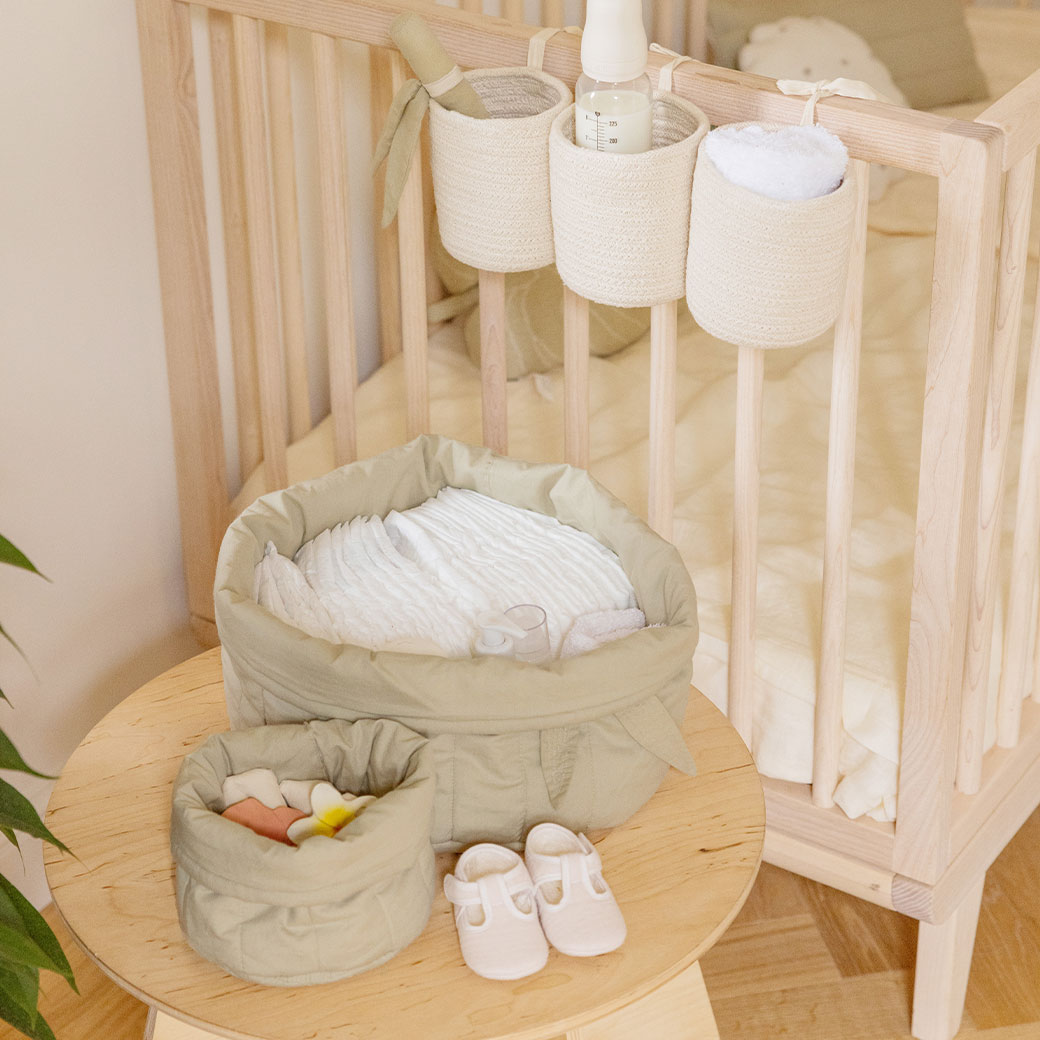 Lorena Canals Bambie Quilted Baskets on a table next to crib  in -- Color_Olive