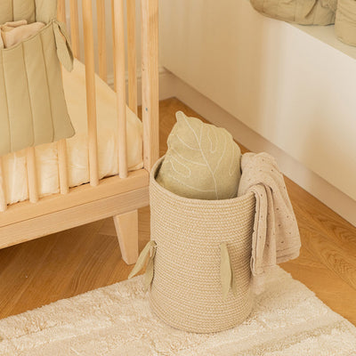 Upper view of Lorena Canals Bamboo Cane Basket next to a crib with blanket inside 
