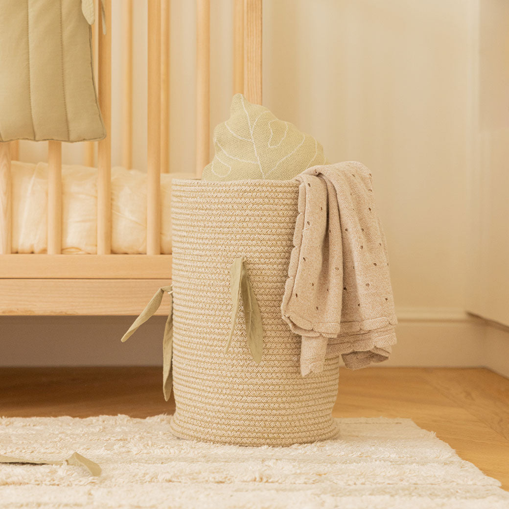Lorena Canals Bamboo Cane Basket next to a crib with blanket inside 
