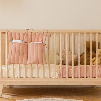 Distant view of Lorena Canals Benjamin Pocket Hanger on a crib in -- Color_Nude