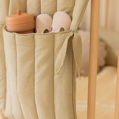 Closeup view of Lorena Canals Benjamin Pocket Hanger on a crib in -- Color_Olive