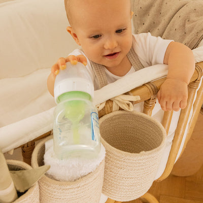 Closeup view of a baby in a crib equipped with the Lorena Canals Bobby Crib Basket in -- Color_Vanilla