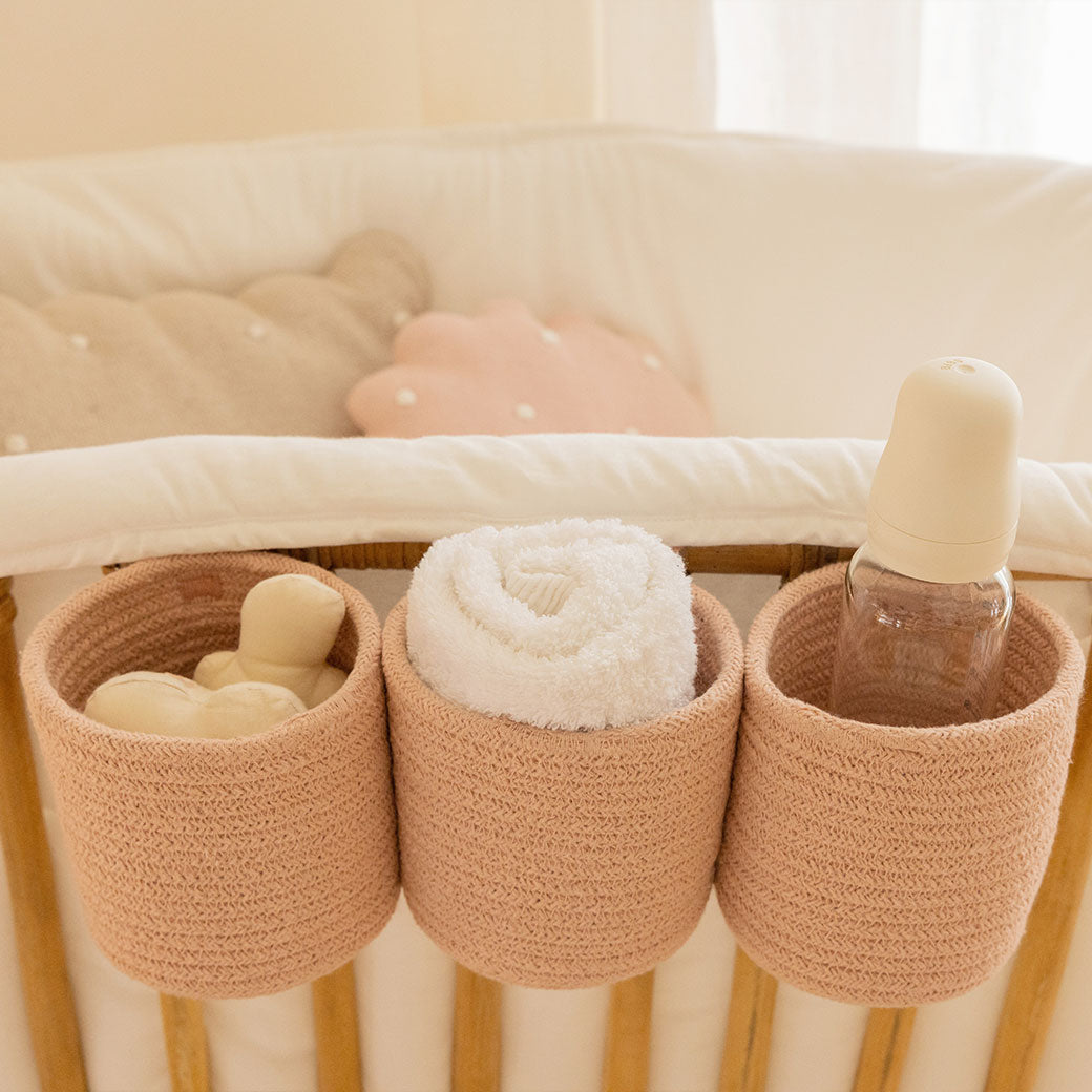 Lorena Canals Bobby Crib Basket hanging on a crib with baby supplies inside  in -- Color_Vintage Nude