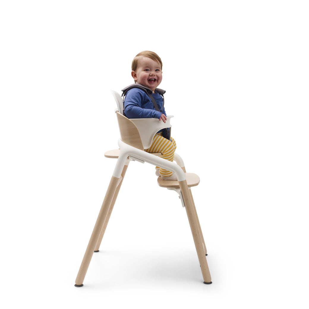Side view of child sitting in a Bugaboo Giraffe High Chair in --Color_Neutral Wood / White