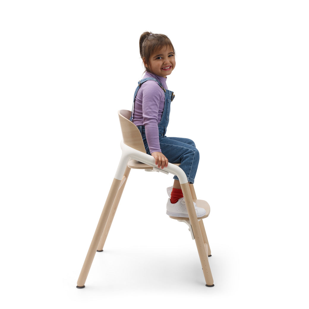 Side view of child sitting in a Bugaboo Giraffe High Chair without baby set in --Color_Neutral Wood / White