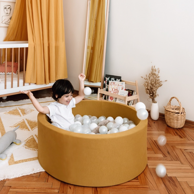 Boy laughing and playing in mustard ball pit and throwing balls -- Lifestyle