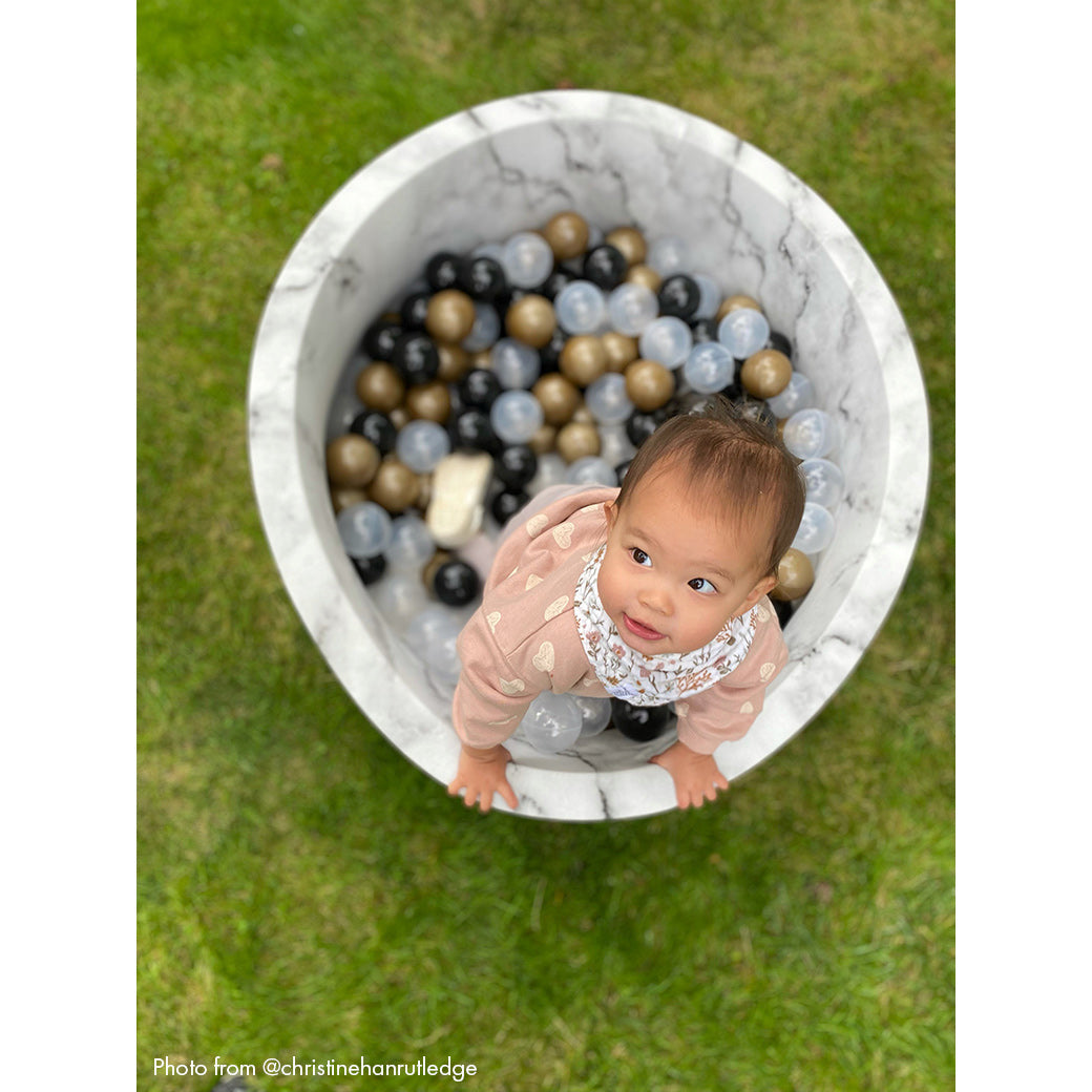 Baby standing up in marble ball pit -- Lifestyle