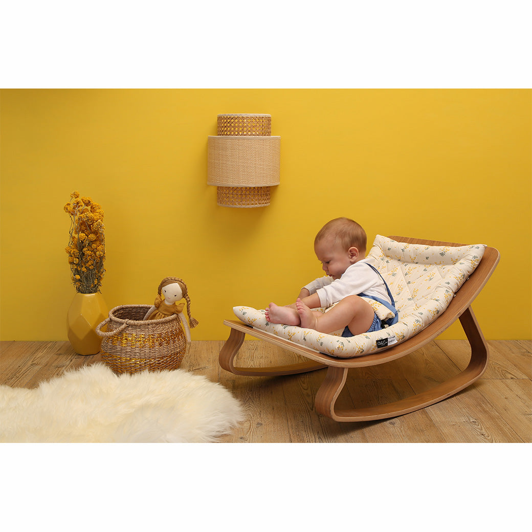 Baby playing on the Charlie Crane LEVO Baby Rocker in -- Color_Garbo And Friends Mimosa _ Walnut