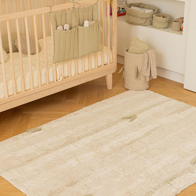 Lorena Canals Bamboo Forest Washable Rug i a baby room next to a crib and a basket 