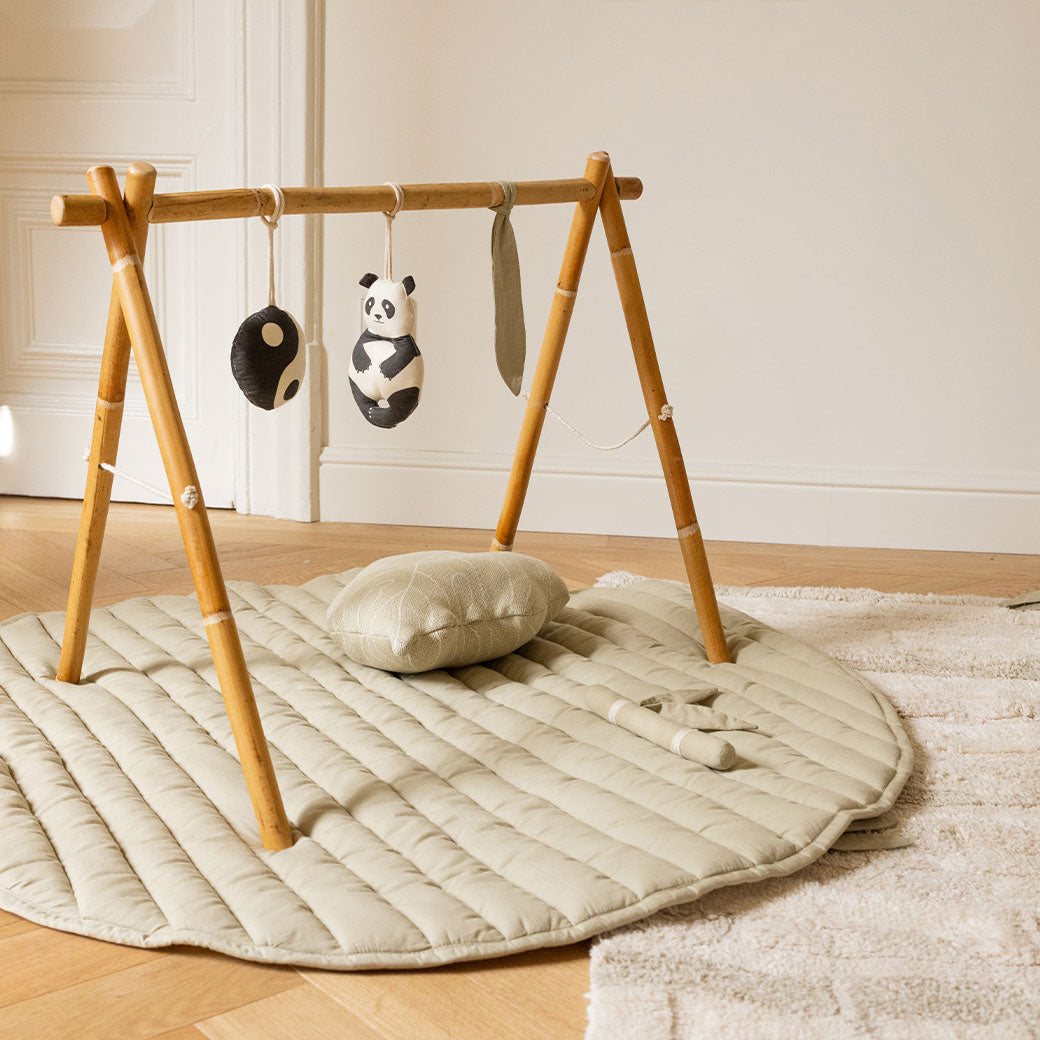 Lifestyle view of the Lorena Canals Products Bamboo Leaf Playmat with pillow and toys on top. 