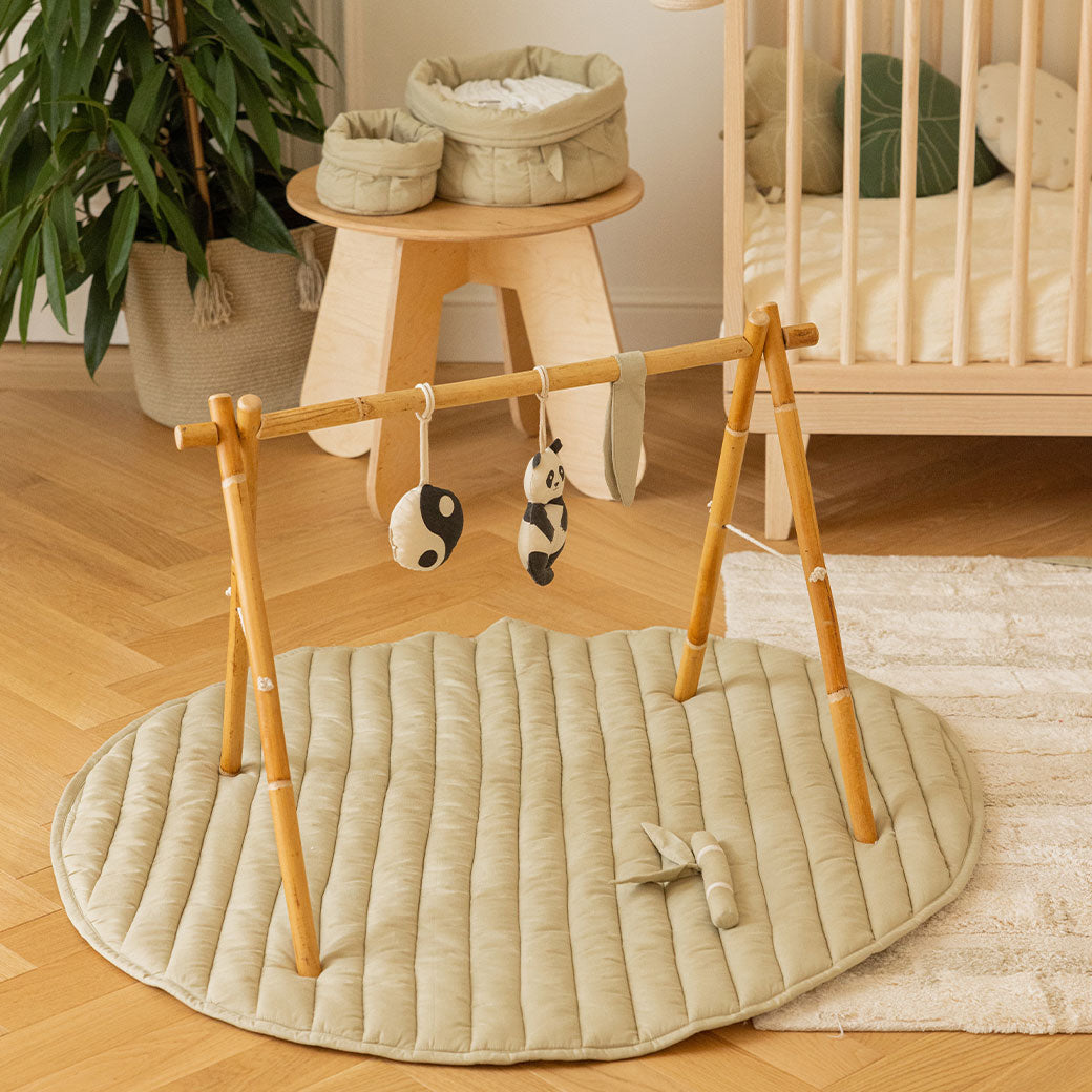 Lorena Canals Products Bamboo Leaf Playmat in a child`s room next to a crib
