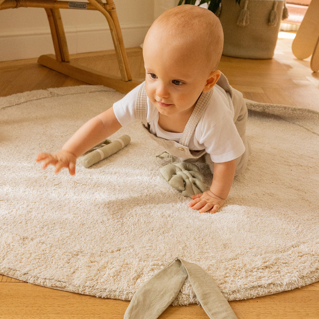 A baby playing on the Lorena Canals Bamboo Leaf Washable Rug