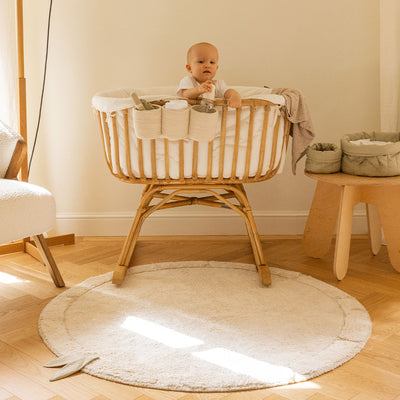 Lorena Canals Bamboo Leaf Washable Rug in a child`s room next to a crib with baby inside 