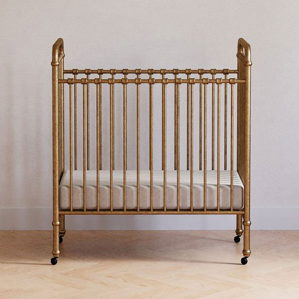 Front view of Namesake`s Abigail 3-in-1 Convertible Mini Crib in a room in -- Color_Vintage Gold