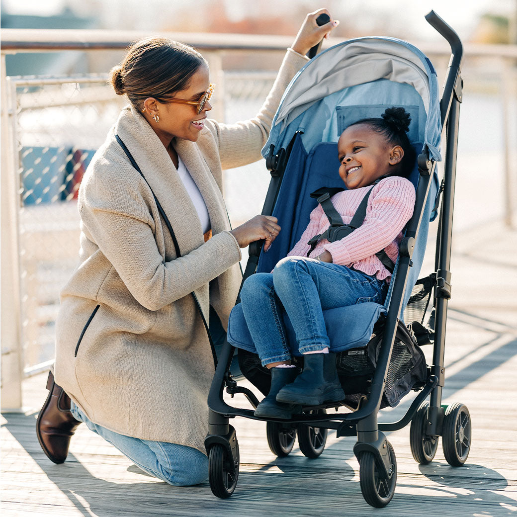 Mother kneeling next to child in UPPAbaby G-Luxe Stroller in --Color_Charlotte